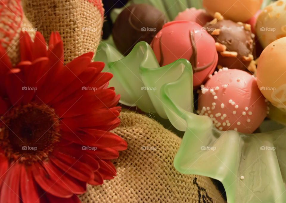 Closeup of bowl of chocolate truffles next to burlap bag with red Daisy gourmet vintage chocolate background 