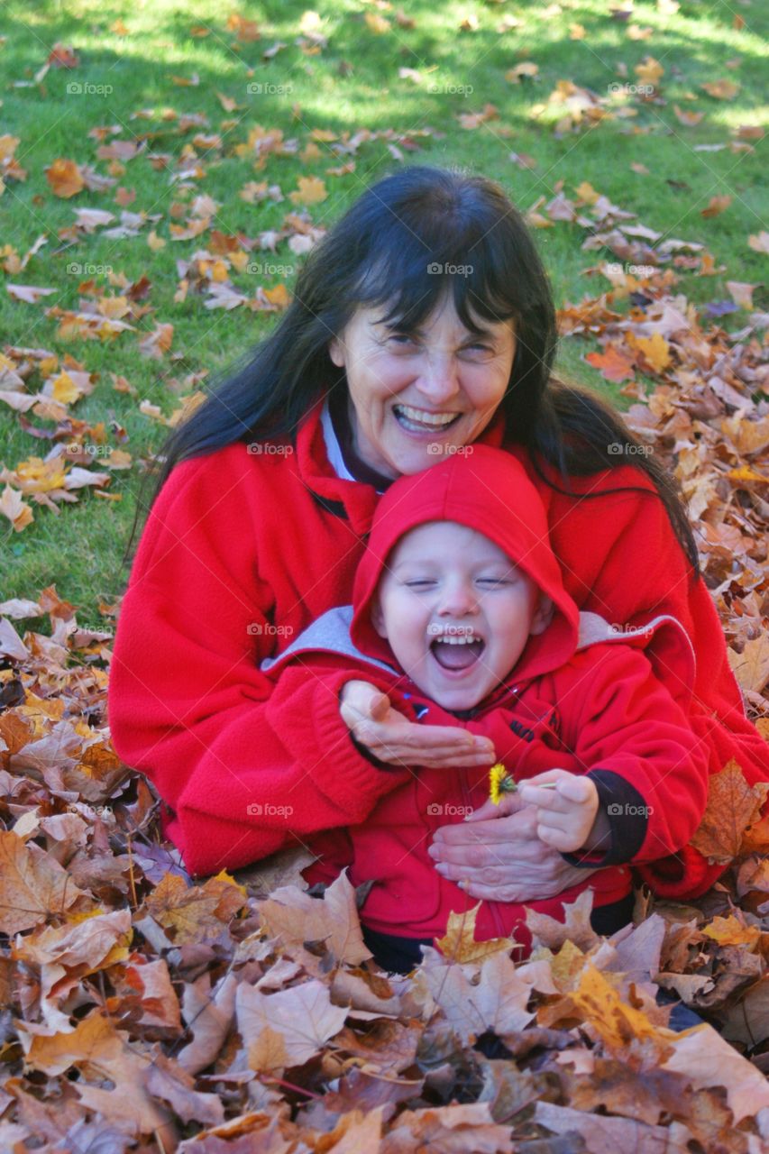 Grandmother and grandchild sitting on autumn leaves