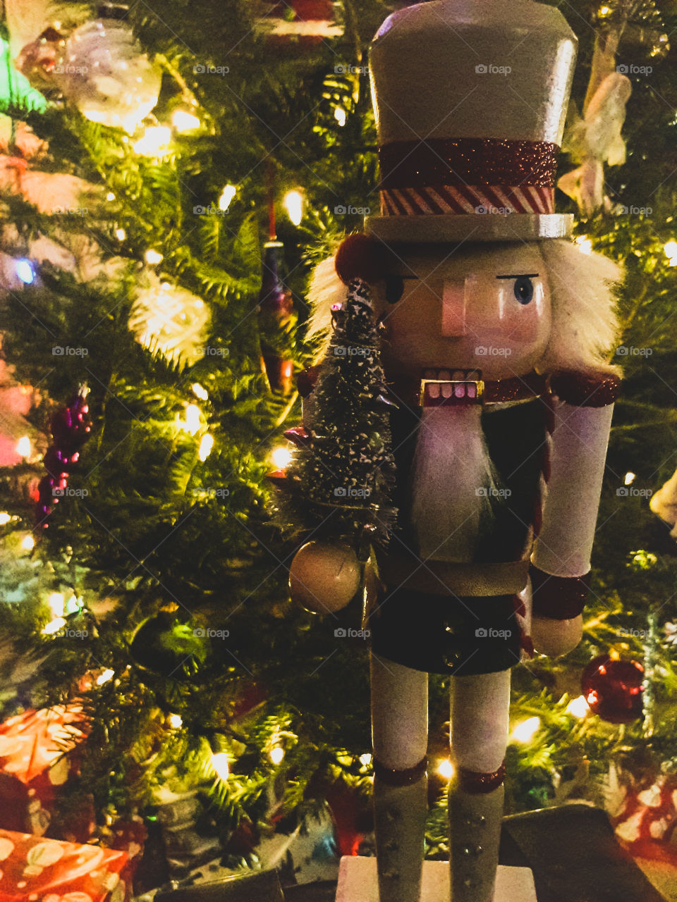A Nutcracker Christmas decoration is softly illuminated, by the Christmas tree.