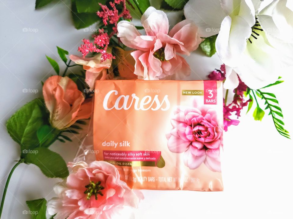 The new look Caress bar three pack of daily silk on a white background with a few complementary florals.