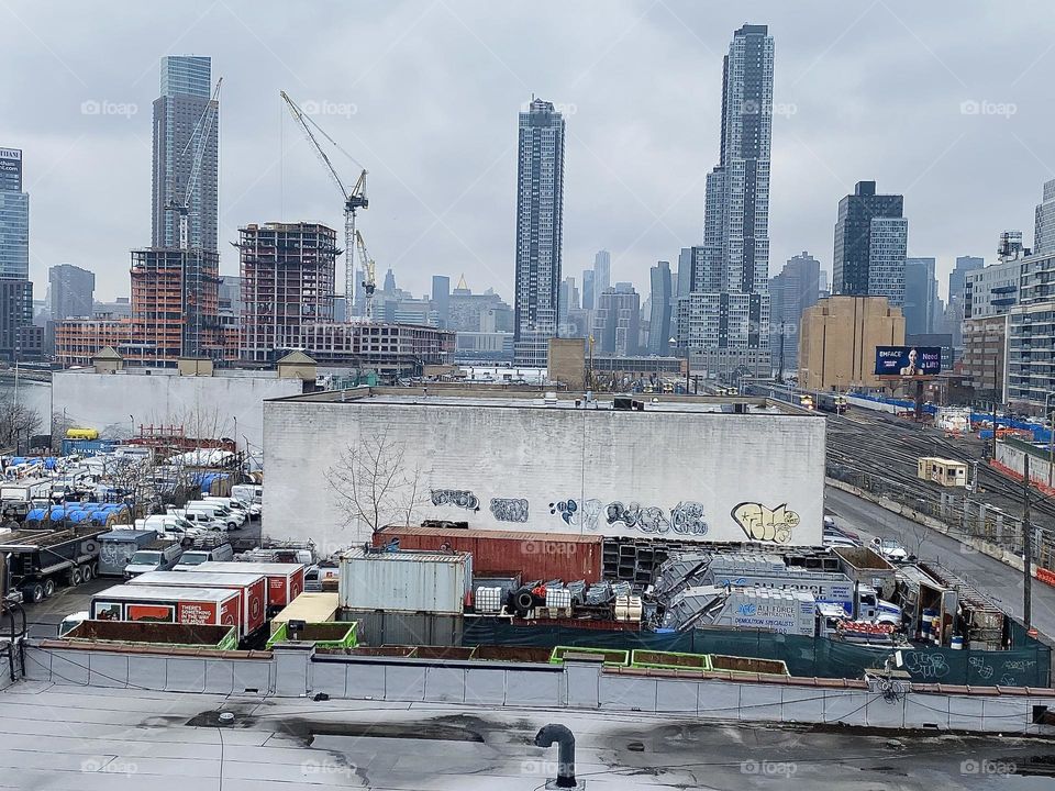 The “Manhattan skyline” can clearly be seen from here in LIC, Queens even on a hazy day. The towering structures in the foreground are “Long Island City’s” own skyscrapers. 2023. Hypnotic Productions