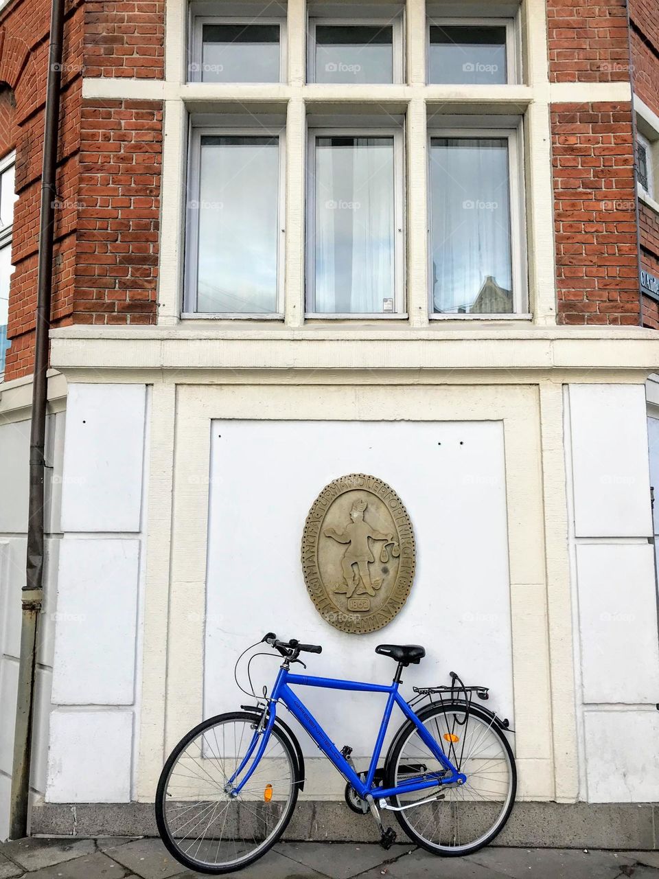 One lonely blue bicycle against the building wall with the coat of arms 