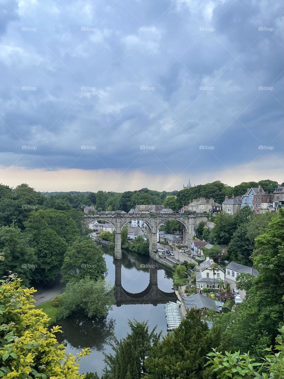 A river runs beneath a stone bridge in the Yorkshire town of Knaresborough, June 2022.