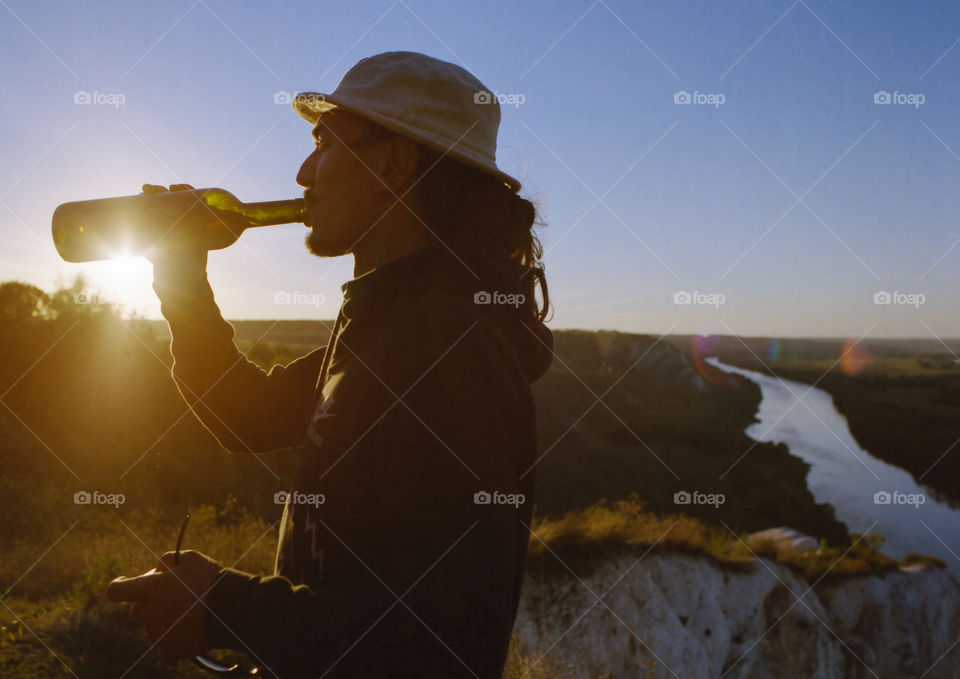 Man drinking from the bottle on sunset