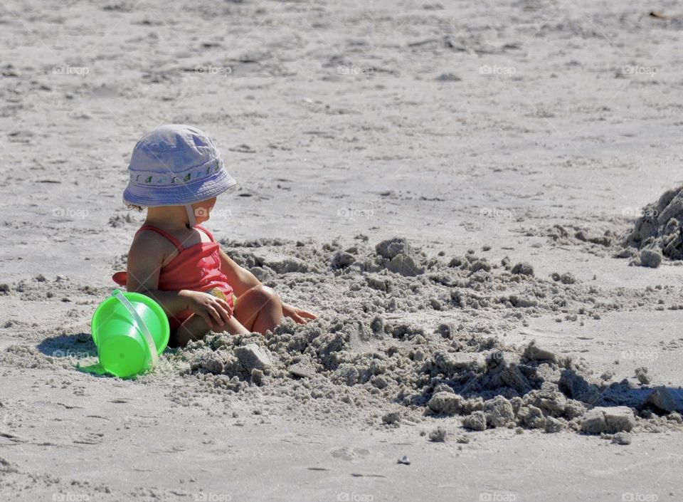 Little girl playing in the sand at the beach 