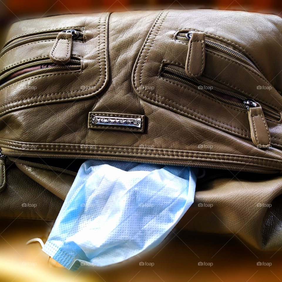 A woman's bag from the compartment of which a medical mask peeps out, which may look like the character "Hulk"