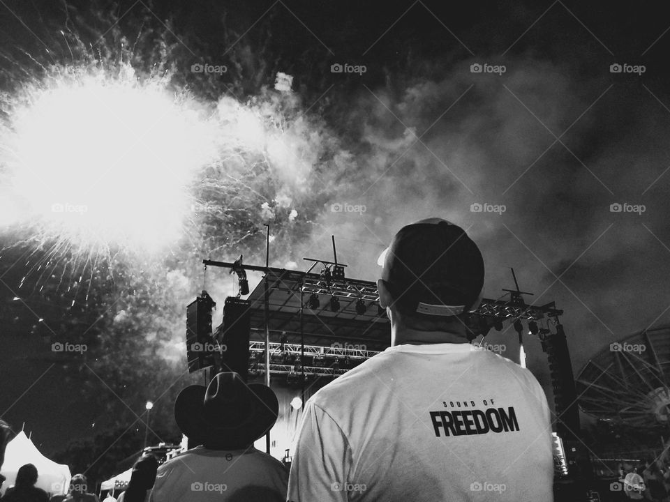 A black and white photo of a man enjoying a July 4th fireworks celebration.