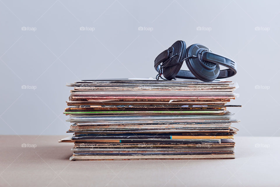 Stack of many black vinyl records, headphones put on the top of vinyls. Copy space for text. Candid people, real moments, authentic situations