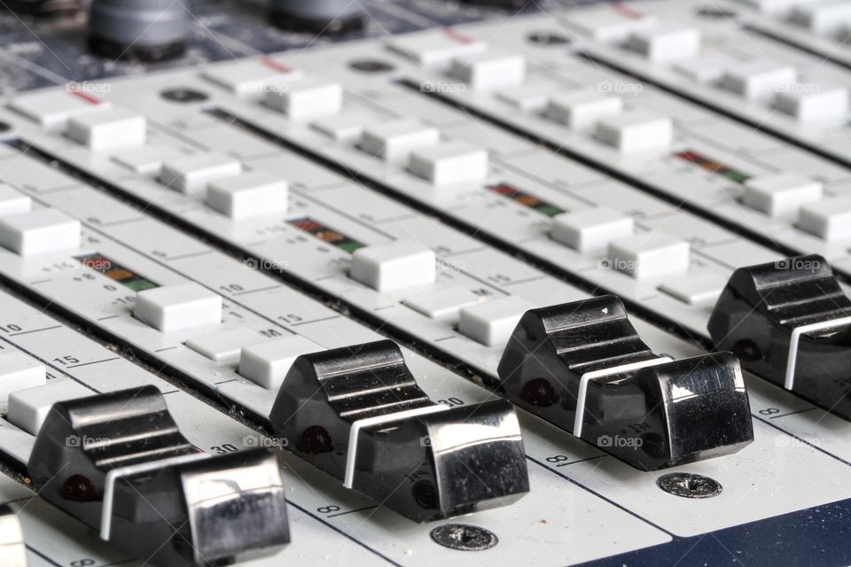 The sliders, buttons and controls of a sound technicians mixing desk used in music and theatre.