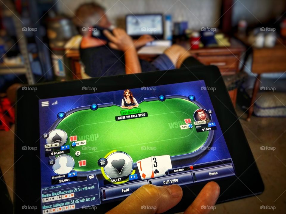 My favorite gadget a Kindle Fire with a game playing poker with a man in the background on his phone in front of his computer