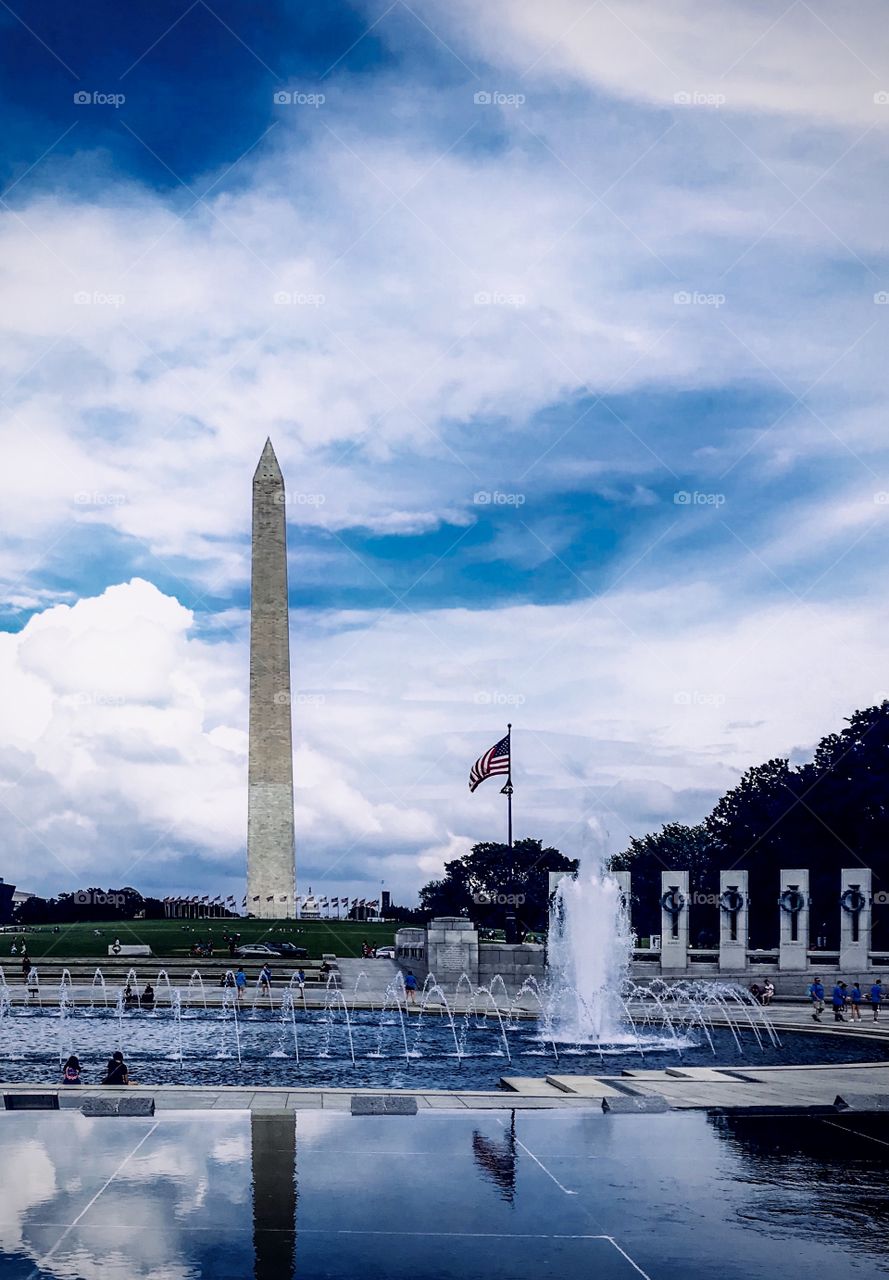 The American flag standing tall with the Washington monument 