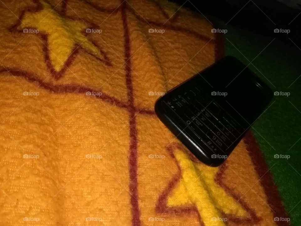 normal keypaded mobile phone on a bed
