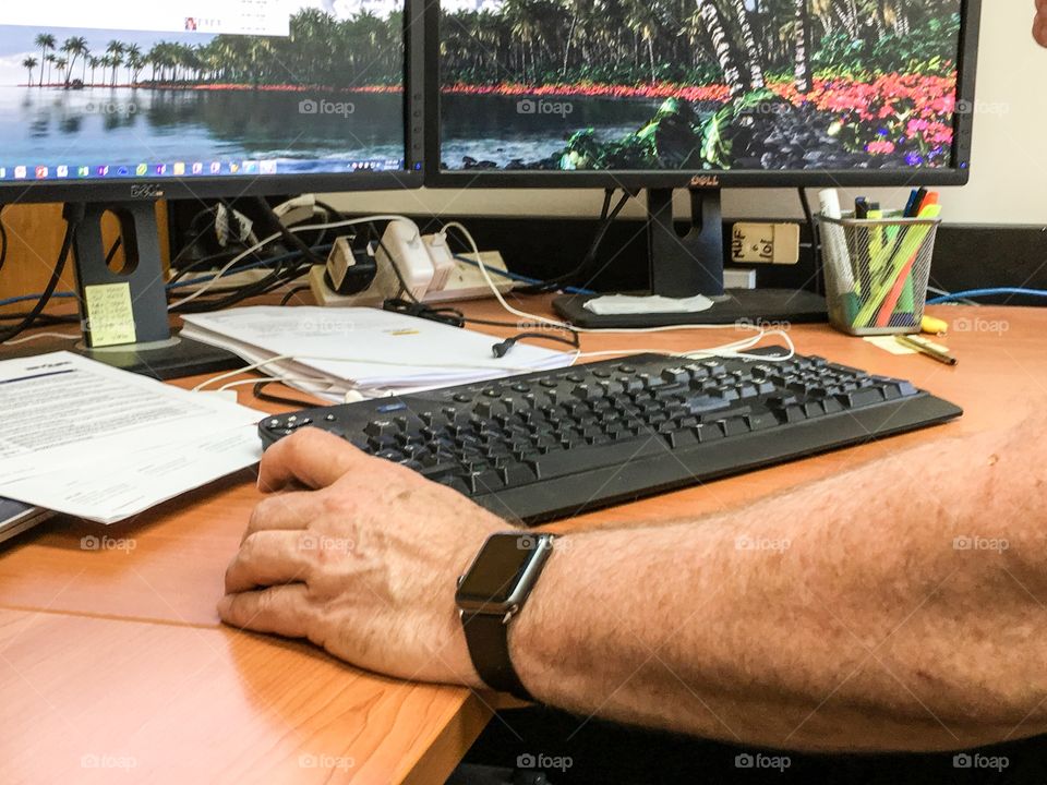 Man at computer desk wearing Apple iWatch two computer screens business desk