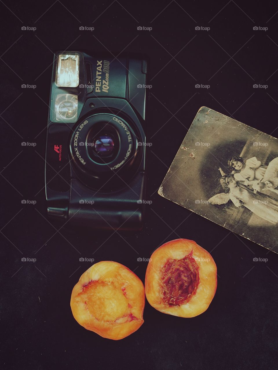 two halves of a peach.  camera.  old black and white photograph of two girls.  Black background.  view from above