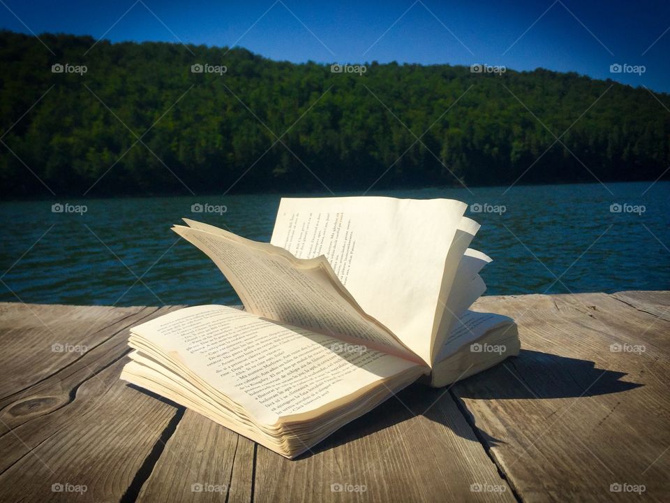Open book on wooden pontoon near the lake