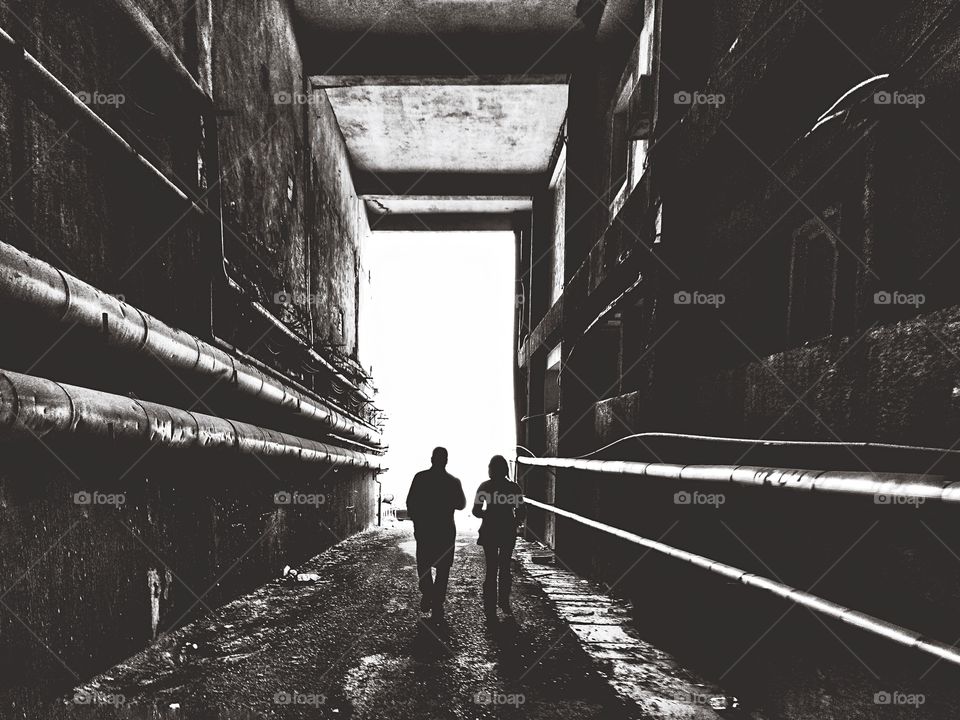 heading toward the light, man and woman in a dark scary but beautiful  tunnel all in black and white 