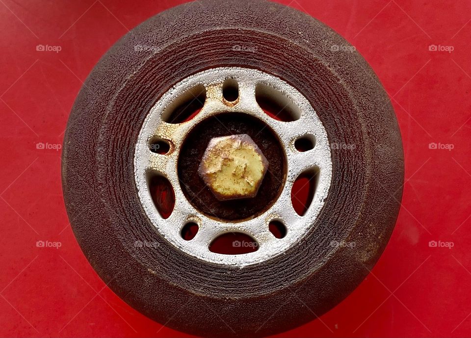 Close up of an old cracked rollerblade wheel on a bright red background