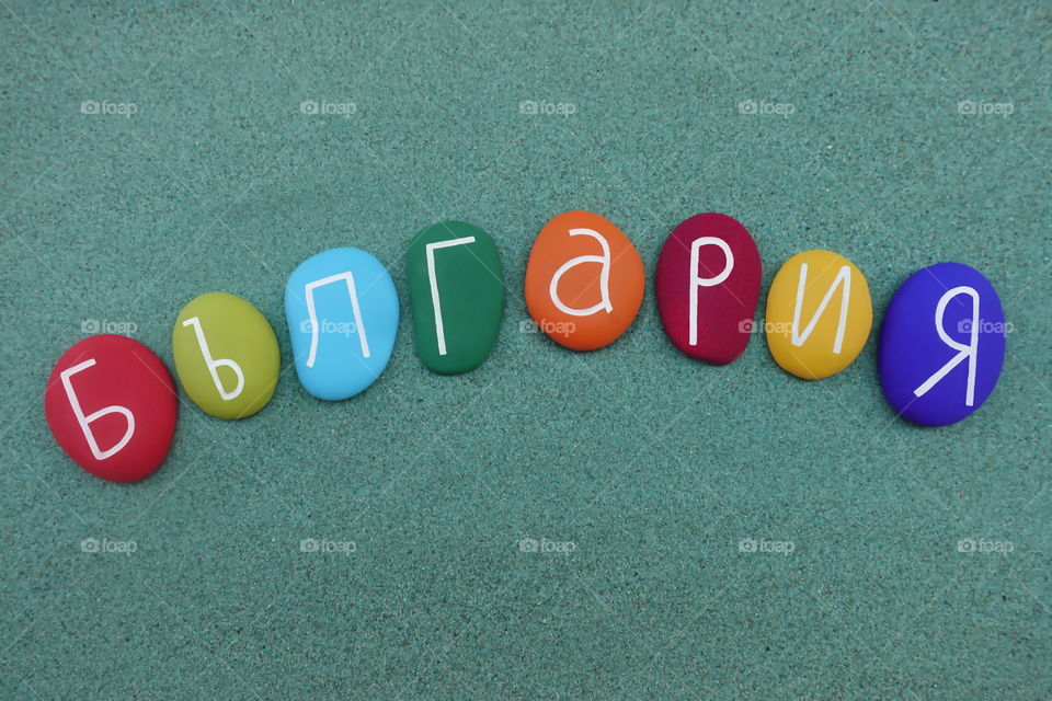 Bulgaria, България, country name in bulgarian language composed with multi colored stones over green sand 