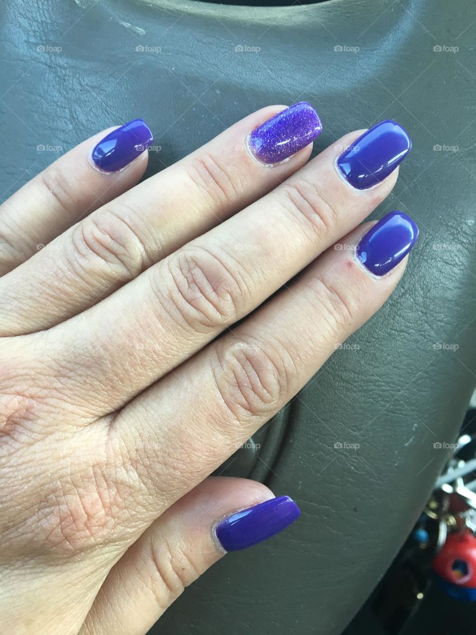 Freshly manicured middle aged lady hand, with shiny bluish purple long gel nails