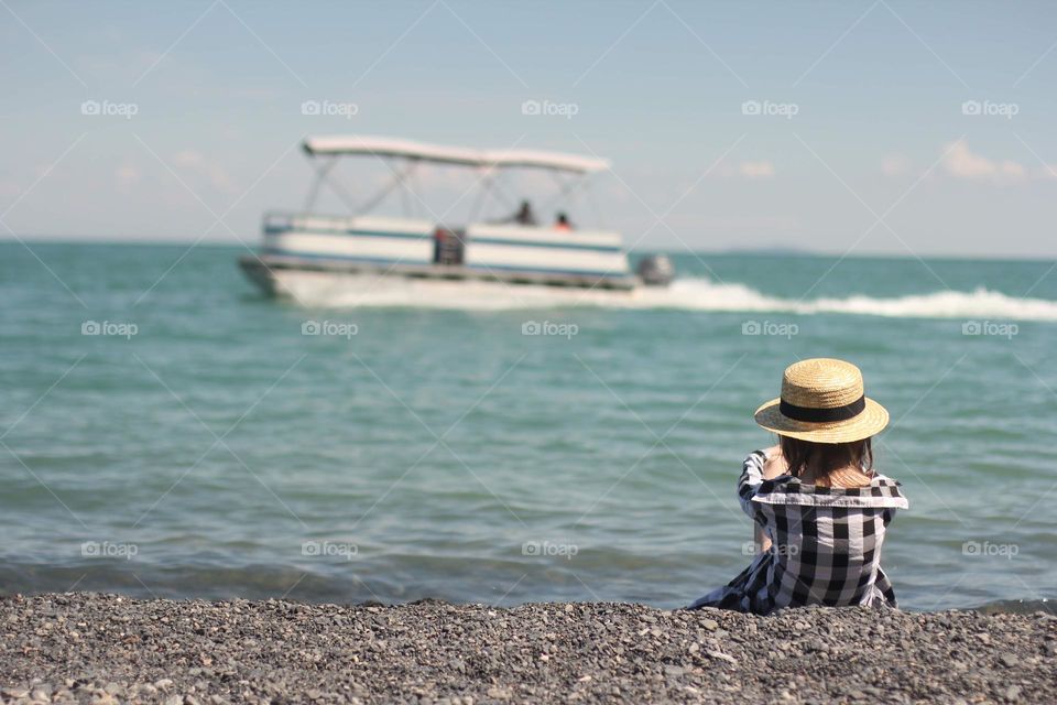 Girl on the shore looks at the passing boat