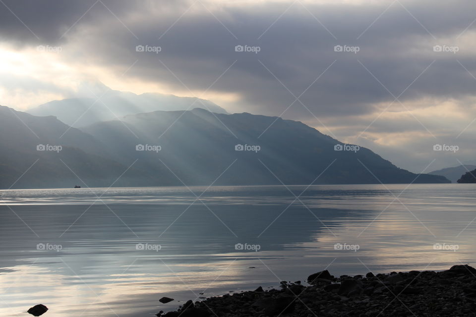 Sun beams coming through the clouds and shining on Loch Lomond, Scotland