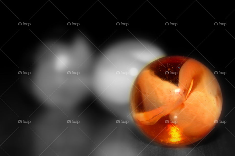 One orange marble in a black and white photo