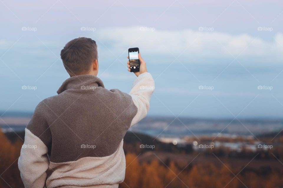 Back view of man taking photo filming video for social media 