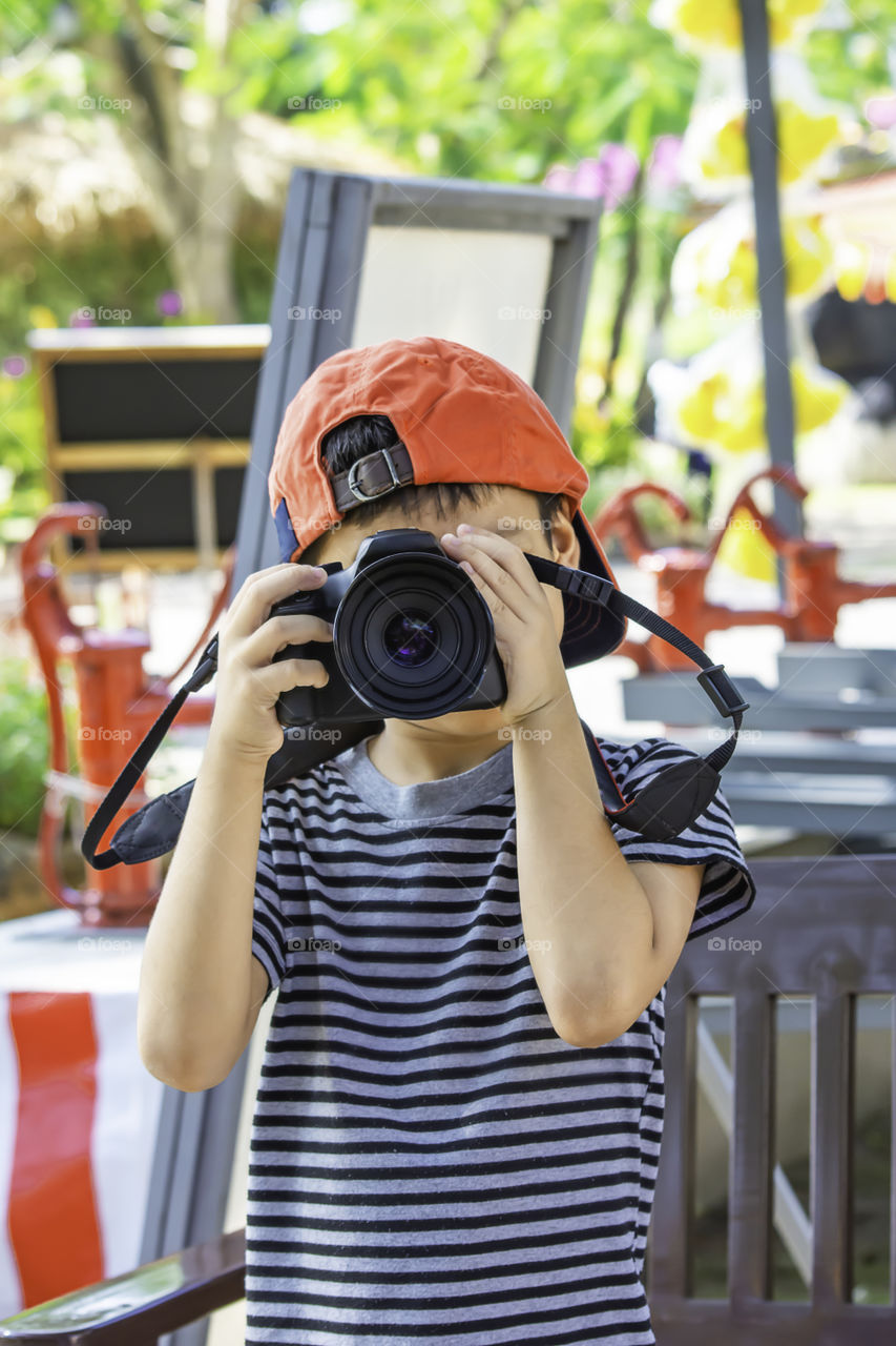 Hand boy holding the camera Taking pictures in park.