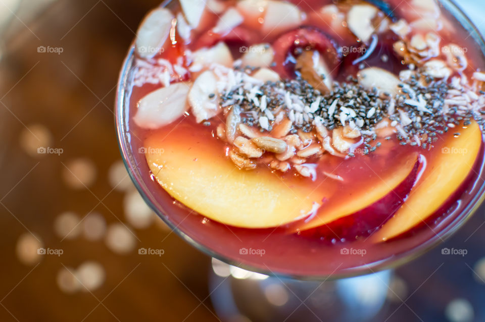 Close-up detail of fresh red berry smoothie bowl full frame garnished with nectarine, chia seeds, oatmeal, almonds, sunflower seed, black cherry and fig healthy eating lifestyle food photography background 