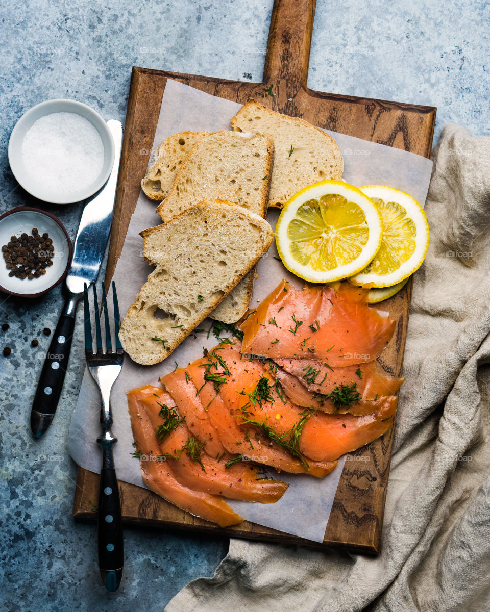 Smoked salmon slices with bread and lemon on wooden board
