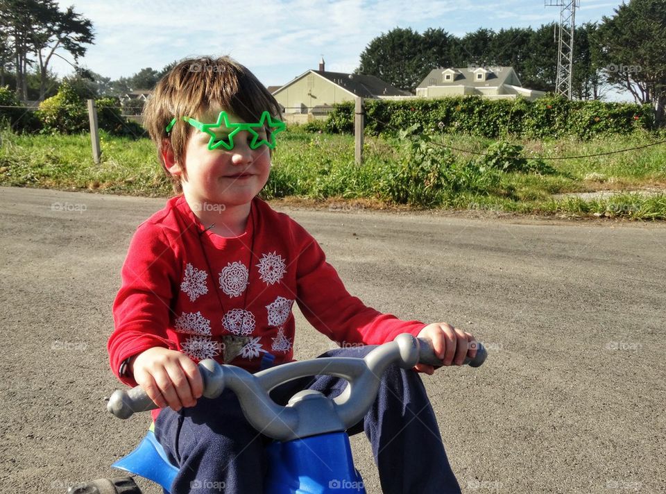 Happy Boy With Crazy Sunglasses Riding A Trike. Boy With Silly Sunglasses Riding A Trike
