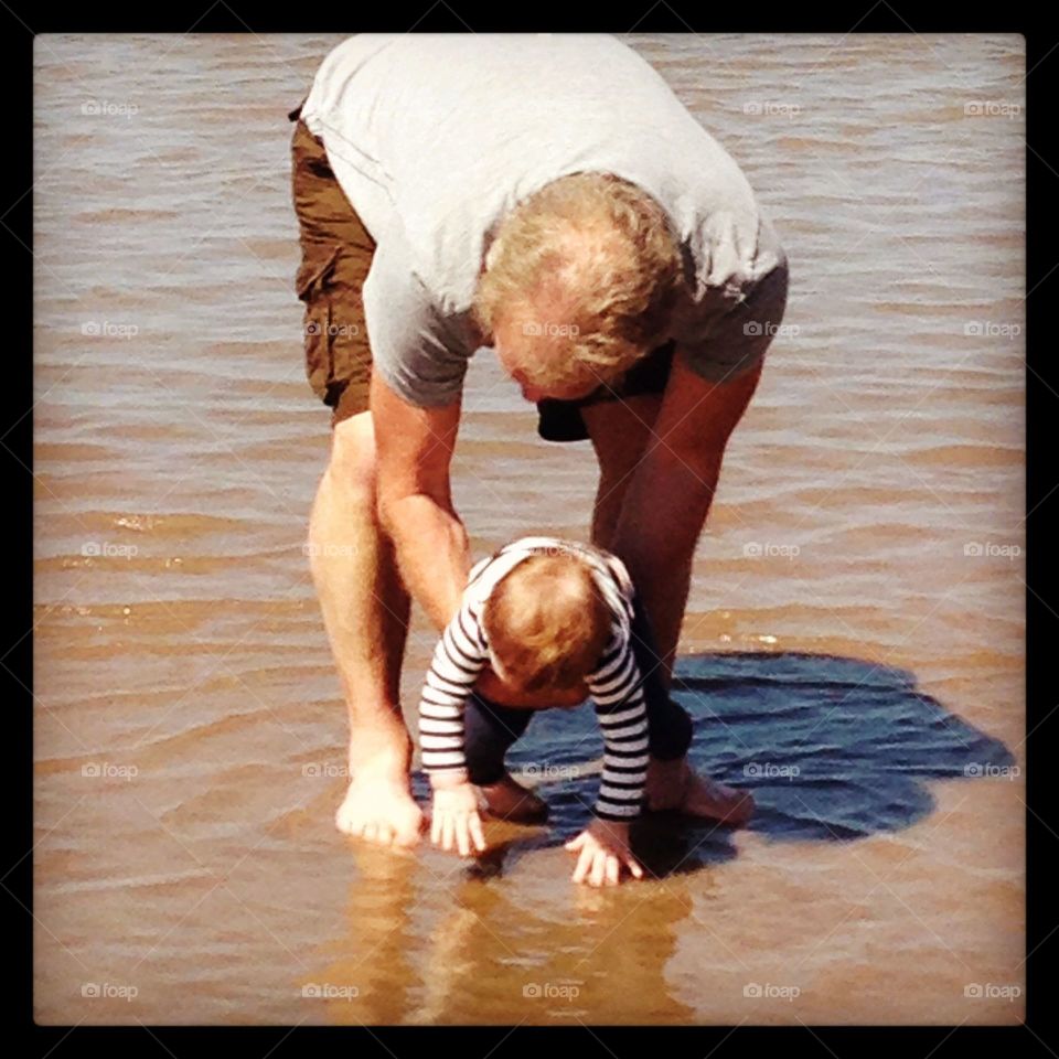 Grandad and granddaughter paddling in the sea for the first time