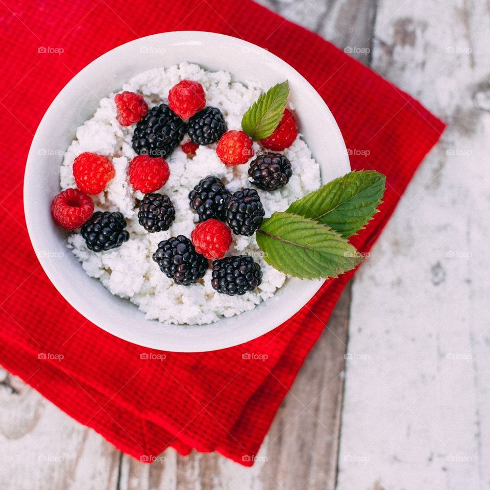Cottage cheese in bowl with raspberries blueberries and mint