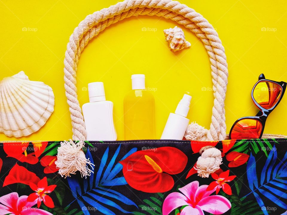 flat lay with colorful beach bag and sunscreen