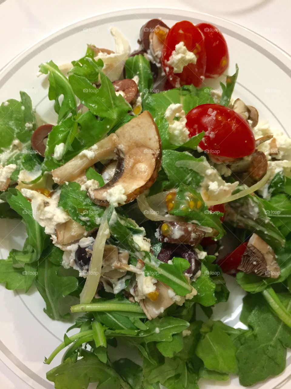 Salad. Arugula salad with grape tomatoes, onion, portobello mushrooms and goat cheese 