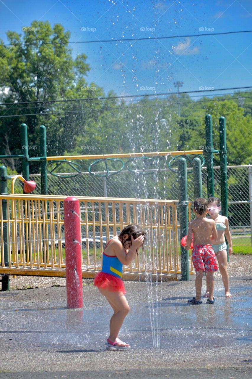 Kids and sprinklers go hand in hand on a hot summers day. One little girl finally getting her head wet after many many attempts.