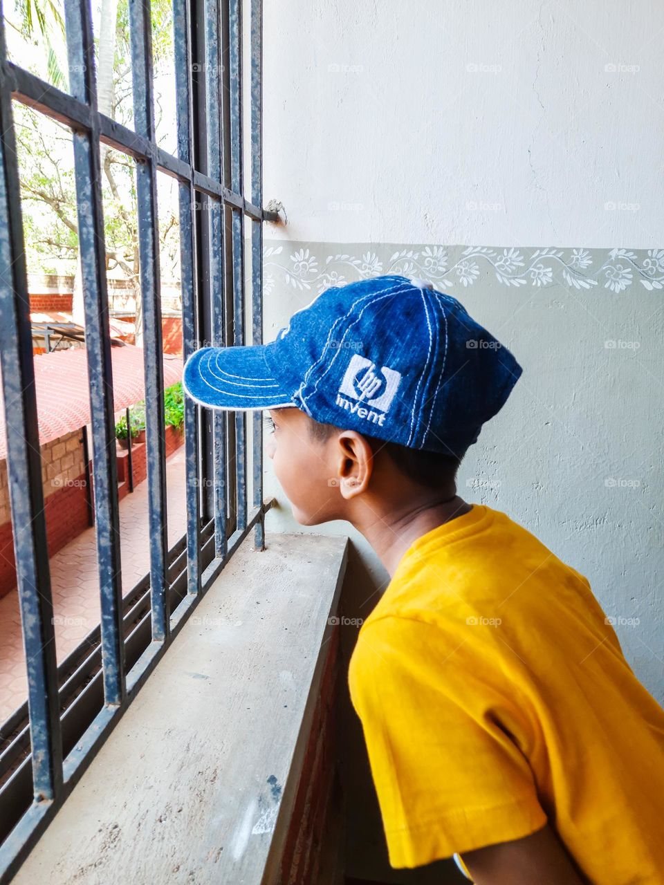 Boy wearing Yellow Colored Tshirt looking through the window