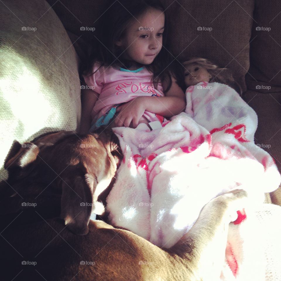 Snuggle Puppy. Little girl with her doll cuddled up with brown dog