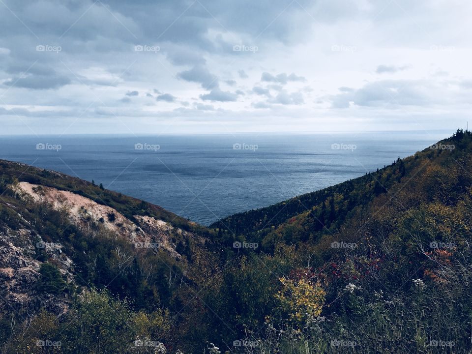 A scenic view of the ocean between two rolling hills, in Cape Breton, Nova Scotia. 