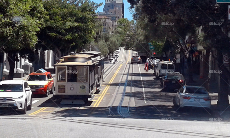 a stereotypical picture of San Francisco with a trolley going up, or down, a hill.