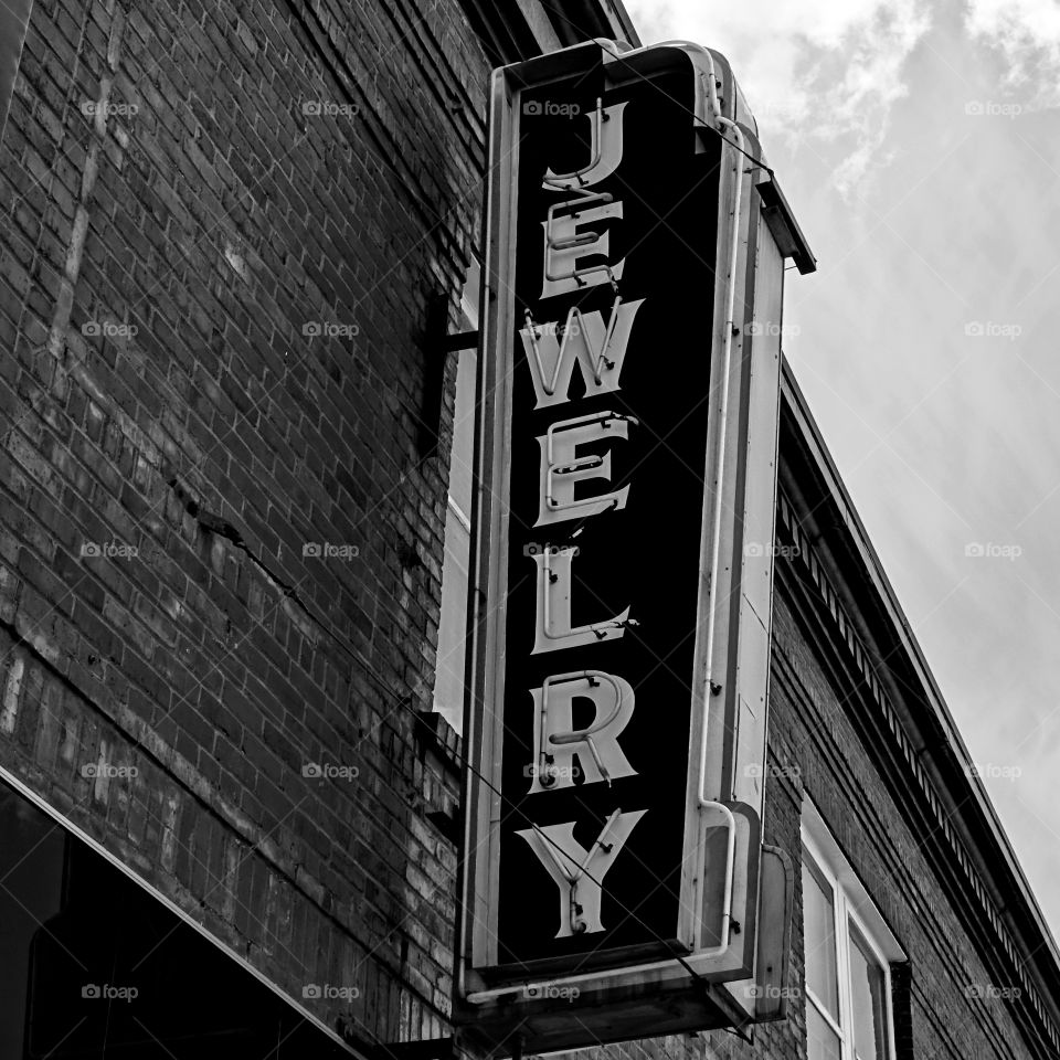 An old neon jewelry sign hangs from a brick building in a small town in Oregon where a lot of the past has been frozen in time. 