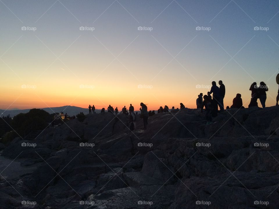 People enjoying sunset at rocky coast