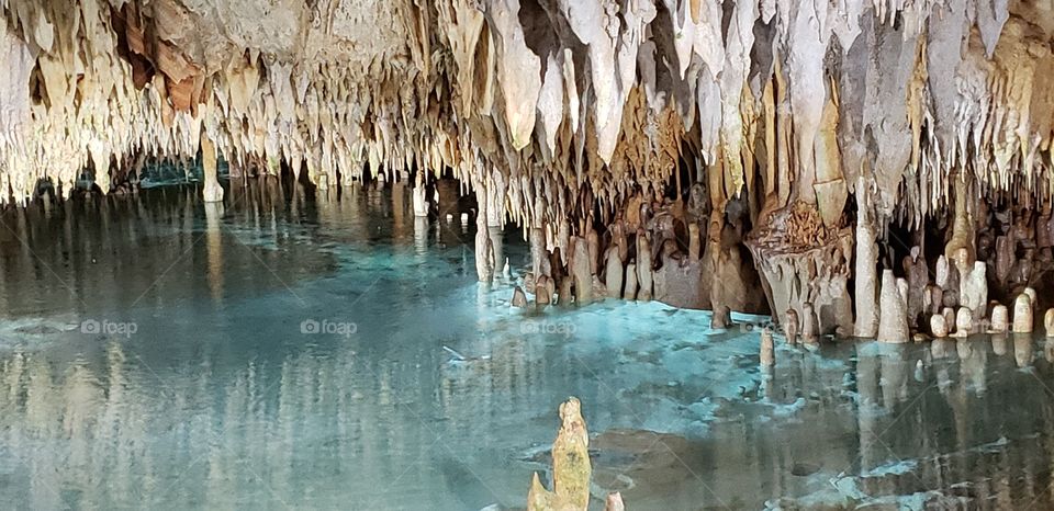 exploration of underground mineral river, translucent blue with a ceiling of stalactites