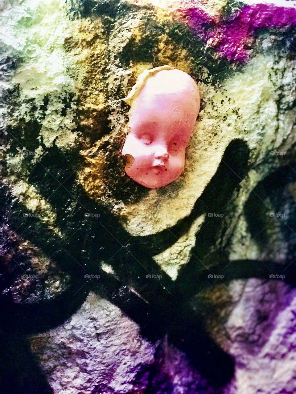 Creepy plastic doll head on a spray painted rock in SOHO, New York City 