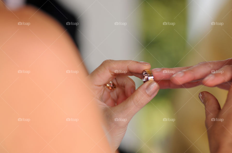 Bride and groom hands with rings in focus background
