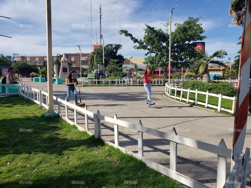 Niñas (mi hija y mi sobrina) Patinando en la plaza central de ciudad. en La Ceiba, Atlántida. Honduras. en un día de verano soleado.