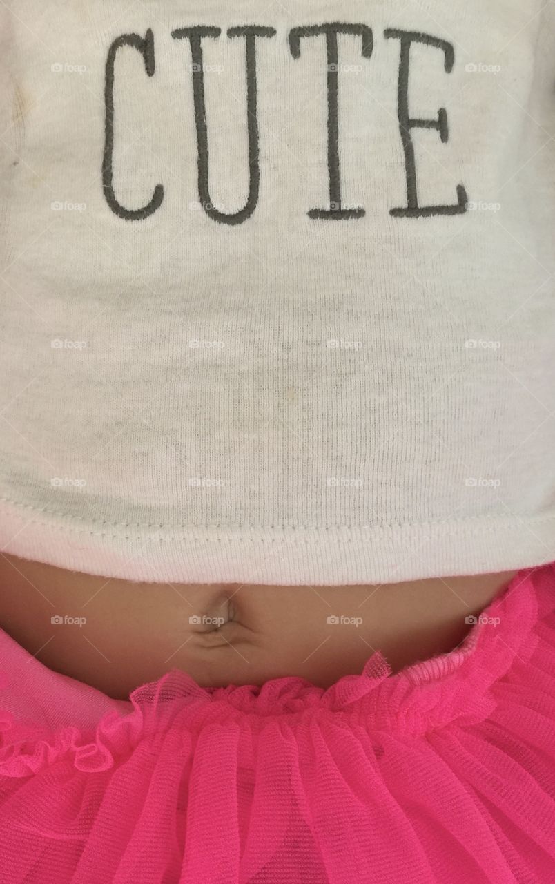Closeup detail of infant baby child navel belly button with white cute T-shirt and hot pink ruffle tutu skirt