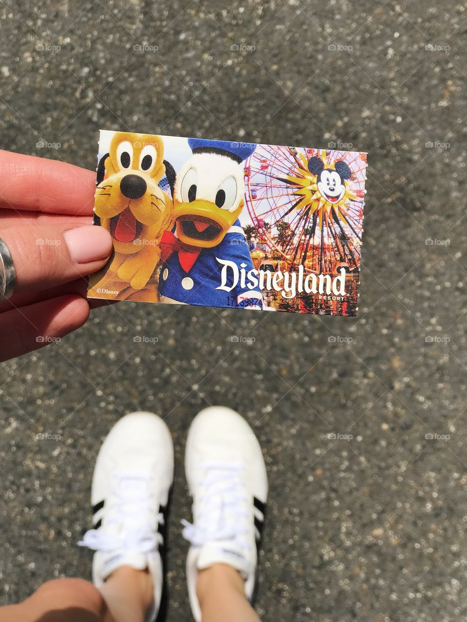 Holding a Disneyland ticket card for the day with shoes in shot
