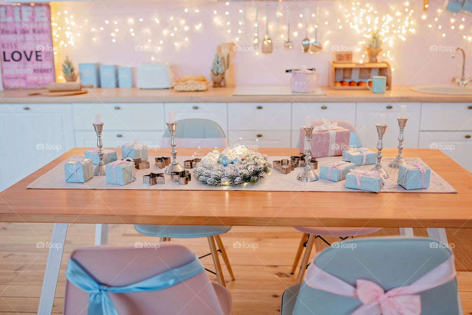 Festive winter cozy kitchen interior with garlands, decorations and gifts.  Christmas dinner at the decorated table.