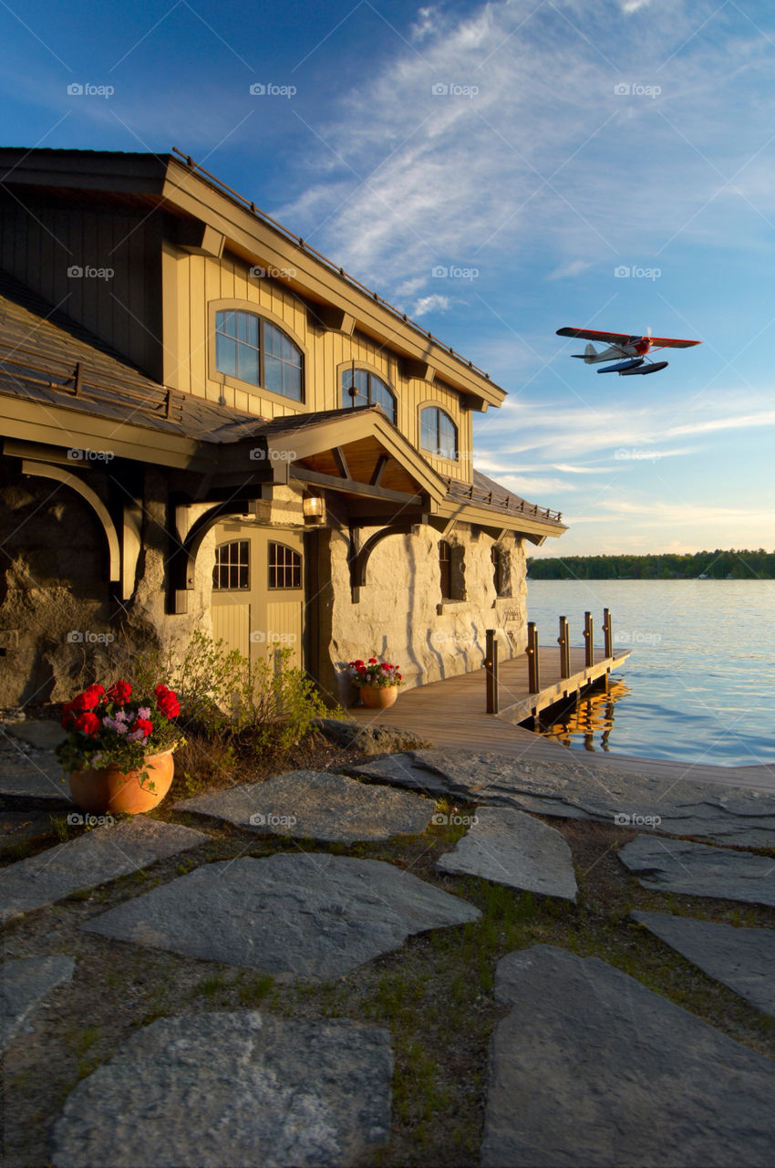Plane flying by boat house on Lake Winnipesaukee